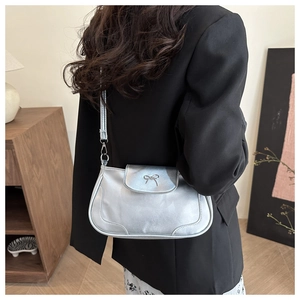 Détail du sac argenté métallisé avec nœud délicat et finition en similicuir lisse