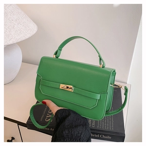Detail of bright green leather handbag with gold rotary lock and top handle