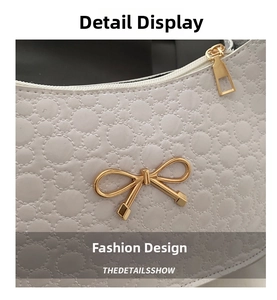 Detail shot of white embossed PU leather texture and gold metal bow clasp on the handbag