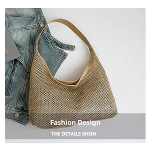Detail of golden woven mesh hobo bag with a light brown leather strap and curved shape