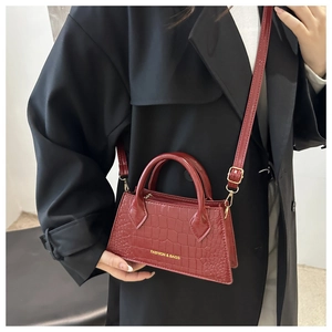 Detail of red crocodile texture handbag with gold zipper and fashion text logo