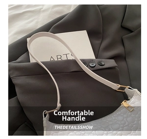 Close-up of white embossed leather shoulder bag with gold metal hardware and slim strap