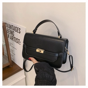Detailed shot of a black leather handbag featuring a secure gold metallic twist lock closure