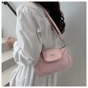 Gros plan du sac baguette rose avec un nœud en métal argenté et une bandoulière amovible