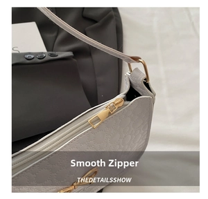 Detail of smooth gold zipper and quilted pattern on white faux leather shoulder bag