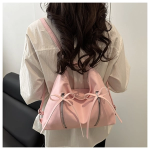 Sac à dos rose à nœuds montrant la texture en nylon imperméable et les détails zippés