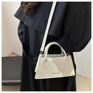 Detailed macro view of white crocodile pattern handbag featuring a metal fashion logo