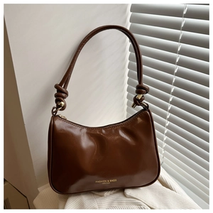 Close-up of dark brown hobo bag with oily leather texture and knotted handle detail