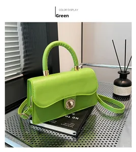 Détail d'un sac en cuir vert avec fermoir tournant doré et poignée supérieure arrondie