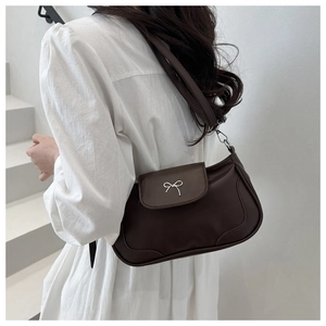Close-up of a dark brown leather underarm bag with a silver bow buckle on the shoulder