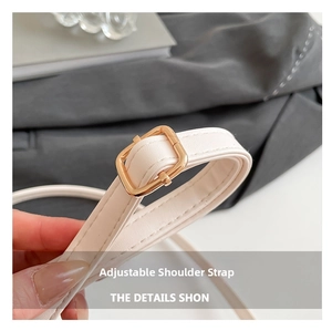 Détail d'une bandoulière réglable en cuir crème avec boucle en métal doré poli sur le sac