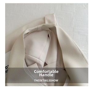 Detail of wide comfortable handle on cream white lychee grain leather tote bag