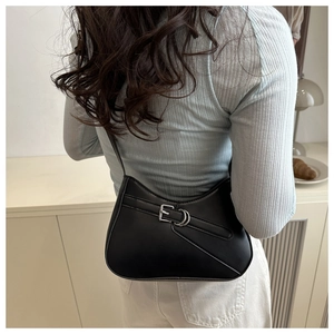 Close-up of minimalist black leather underarm bag with silver metal buckle and strap