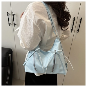 Détail du sac à bandoulière bleu clair style balletcore avec nœuds blancs et zips