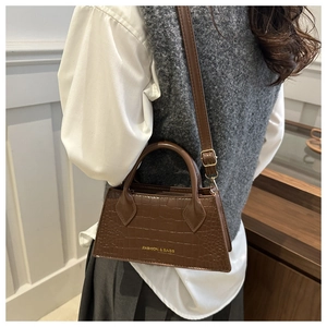 Detail view of a vintage dark brown crocodile embossed crossbody bag with gold lettering