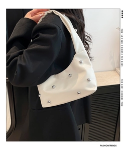 Macro detail of white crescent underarm bag featuring silver rivet stud embellishments