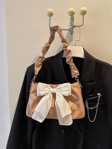 Detail of khaki PU leather pleated bag featuring a large white ribbon and scrunchie strap
