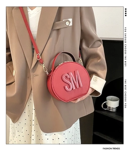 Detail of red circular crossbody bag with SM letter metal hardware and gold buckles