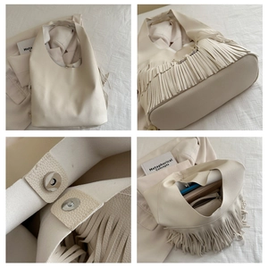 Detail of cream tassel tote bag featuring litchi grain leather and magnetic closure