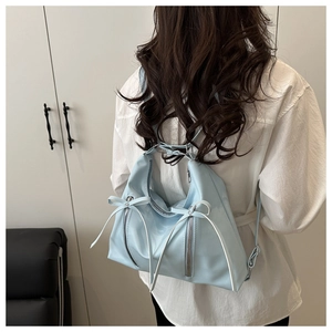 Rear view of a light blue glossy bow backpack on model with dual silver vertical zippers