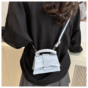 Close-up of a mini light blue marble pattern handbag with golden hardware and top handle