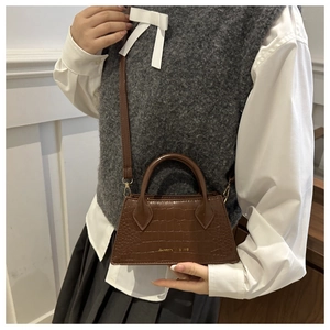 Detail of vintage brown crocodile texture and gold logo on the elegant handbag