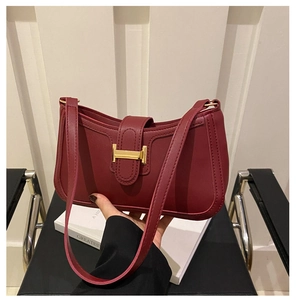 Détail du sac en cuir mat rouge foncé avec une boucle métallique dorée en forme de H
