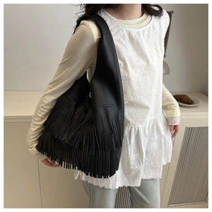 Dettaglio macro della borsa hobo in pelle nera con lunghe nappe eleganti e trama martellata