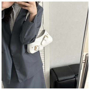 Detail of white PU leather underarm bag with diamond stitching and gold buckle hardware