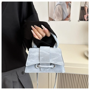 Detail of light blue marble textured mini handbag showing top handle and slim strap