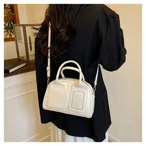 Detail of a minimalist cream-colored leather Boston bag with decorative square stitching