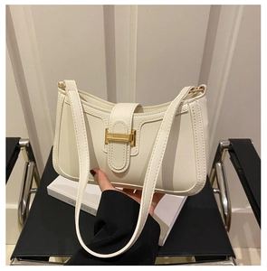 Détail d'un sac à bandoulière blanc crème avec fermoir métallique doré en H et texture lisse