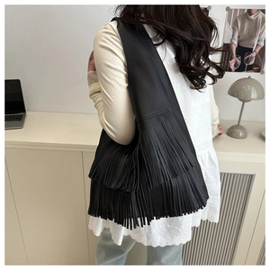 Detail view of the black leather tassel shoulder bag with elegant fringe texture