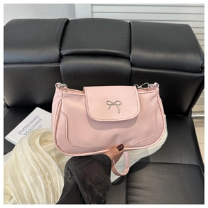 Detail of pink leather handbag featuring a decorative silver metal bow on the front flap