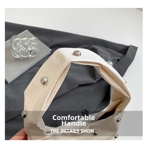 Close-up of off-white leather handbag handle featuring silver metallic stud rivet details