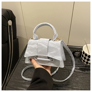 Detail of light blue wrinkled texture handbag with gold hardware and curved base