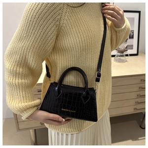 Detail of black crocodile texture handbag worn with casual beige knitwear outfit