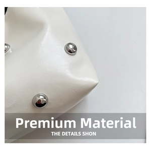 Macro view of white textured leather bag with metallic silver stud rivets craftsmanship