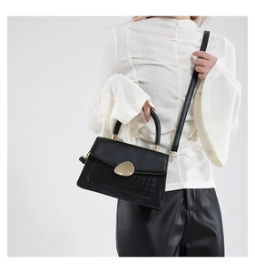 Détail du sac en similicuir noir avec motif crocodile et fermoir galet doré