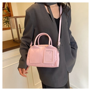 Gros plan d'un sac bowling rose porté en bandoulière avec un tailleur gris chic