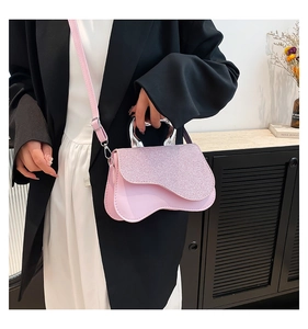 Detail of pink crossbody bag with sequins flap and silver handle on a model