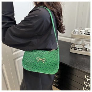 Détail du sac à bandoulière vert citron texturé avec nœud doré porté à l'épaule