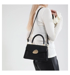 Détail du sac à main noir élégant avec texture crocodile et fermoir en métal doré