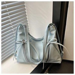 Détail du sac fourre-tout bleu clair avec zips argentés et rubans décoratifs en nœud