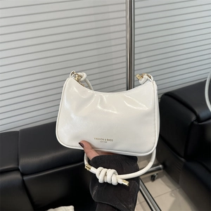Minimalist white leather underarm bag with knotted handle shown in a modern interior setting