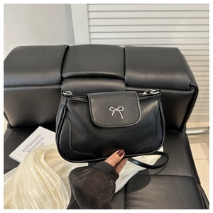 Close-up of the black leather shoulder bag with a silver metal bow accent detail