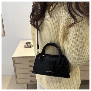 Detail of a black crocodile pattern crossbody bag with a gold Fashion & Bags logo