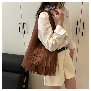 Detail view of large brown fringe tote bag with two-tier tassels and lychee grain leather