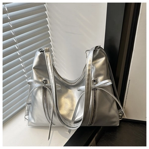 Détail du sac cabas argenté métallisé avec nœud et ombres de lumière naturelle douce