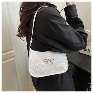 Détail du sac blanc avec texture à pois en relief et boucle de nœud doré